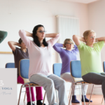 women sitting on chairs doing yoga stretches